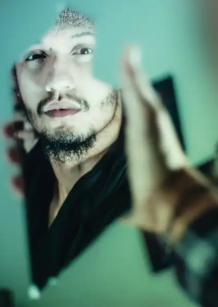 Man looking at himself in a broken mirror.