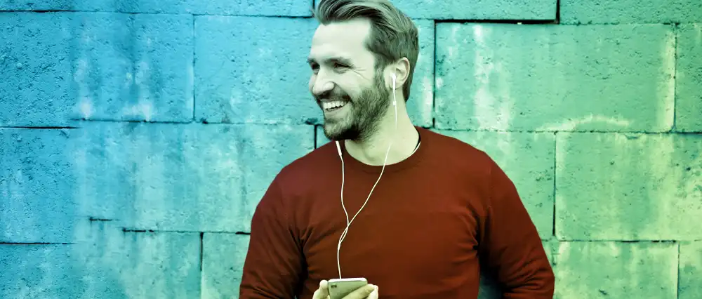 A Happy man leaning on a wall smiling.